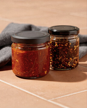 Two Jars of Homemade Chili Oil and Spicy Condiment on Tile