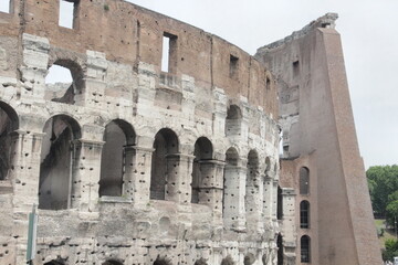 Obraz premium Side angle closeup of the Roman Colosseum displaying stone arches alongside its iconic brick reinforcement wall.