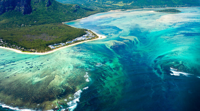 An underwater waterfall off the coast of Mauritius. Aerial view of Le Morne Mountain and a coral reef. A beautiful panoramic view of the tropical island.