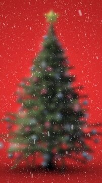 Animation of christmas tree with snow falling on red background