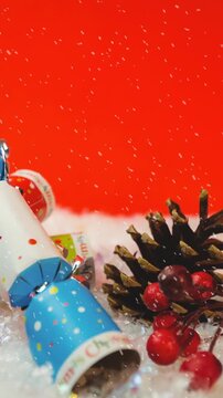 Animation of snow falling against christmas crackers decorations on red