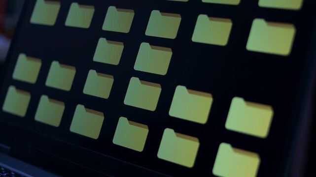 Close-up laptop screen displaying a grid of yellow file folder icons on a dark interface, representing digital file management, data storage, database, document management, and information overload.