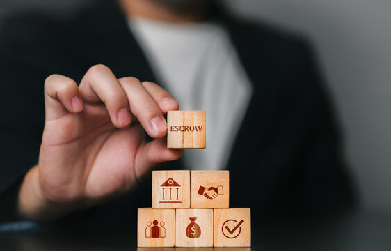 A business professional stacking wooden blocks featuring Escrow money, deposits, or assets deposited with a third party related to finance, teamwork, and success, growth, strategy, and organizational.