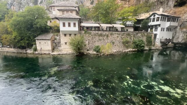 Cinematic horizontal pan right showcasing the historic Blagaj Tekke monastery and river cave