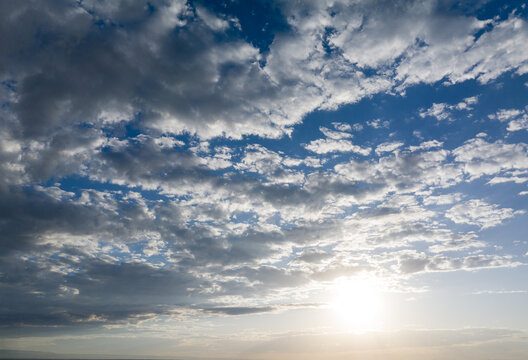 Sunlight pierces through scattered clouds on vast blue sky