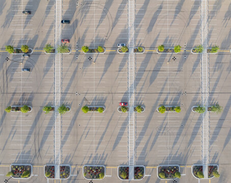 Overhead drone shot shows organized parking area with few vehicles and shrubs