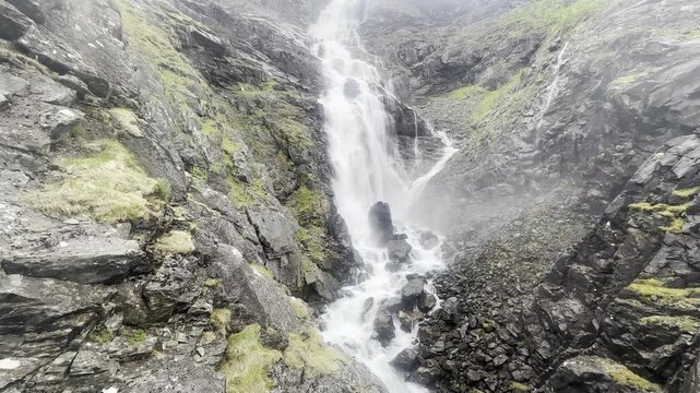 Steady landscape shot of majestic Stigfossen waterfall cascading through Trollstigen mountain pass Norway