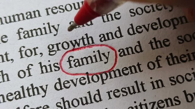 Hand with pen mark circle around to emphasize or highlight family word printed on paper. Symbolic concept represents family instability, insurance, security, safety, protection or problems.
