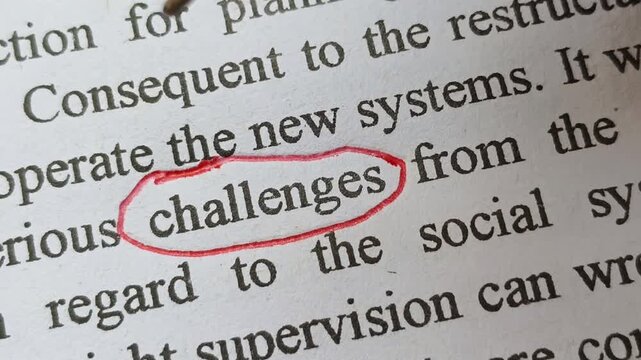 Closeup of hand with red ink pen mark circle around to emphasize or highlight challenges word on article, book or magazine paper. Person facing mental and physical health challenges symbolic concept.