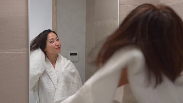 お風呂上がりに濡れている髪をバスタオルで拭く女性