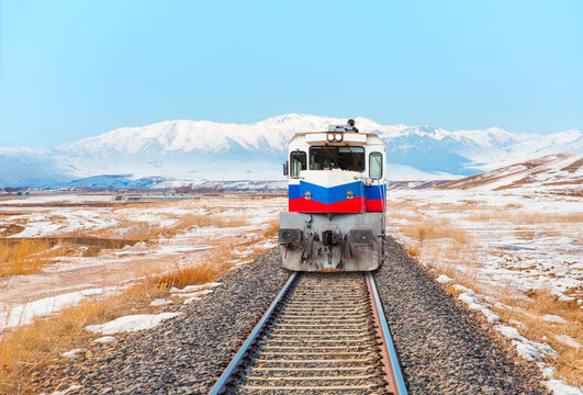 Red and blue diesel train (East express) in motion at the snow covered railway platform - The train connecting Ankara to Kars - Passenger train going through tunnel 