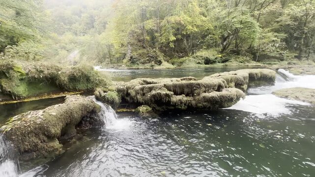 Cinematic landscape shot of small tufa cascades and flowing river water on the Una River