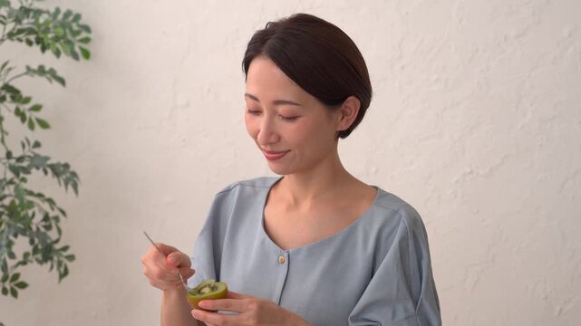 リビングでキウイフルーツを食べる女性