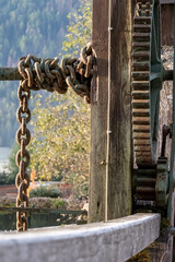 Naklejka premium Rusty Chain and Large Gear Wheel on Vintage Industrial Wooden Structure Outdoor