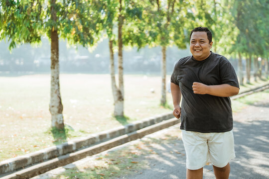 portrait of an overweight man jogging in the park in the morning with copyspace
