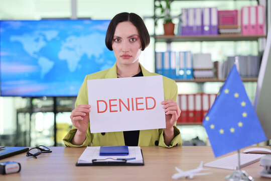 Female clerk displays Denied word for visa decision in European consular office. Worker presents rejection notice confirming refused application