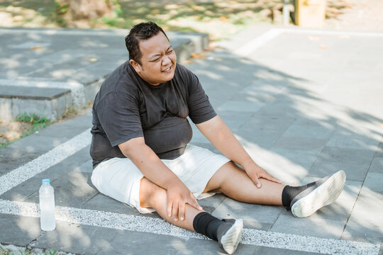 fat man sits down after getting tired while trying hard to lose weight with exercise in the park