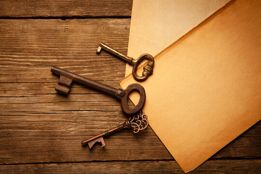 Old keys and envelope on wooden background. Photo in old color image style.