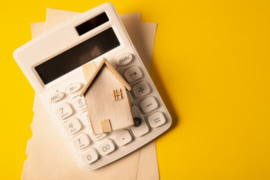 House model and calculator on yellow background. Business and finance concept.