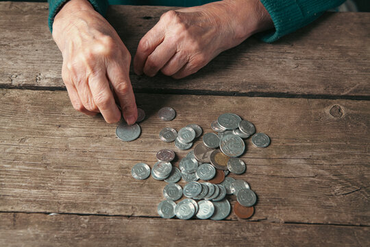 Elderly woman counting coins on a wooden table, closeup