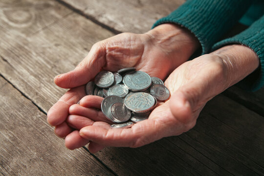 Elderly woman counting coins on a wooden table, closeup