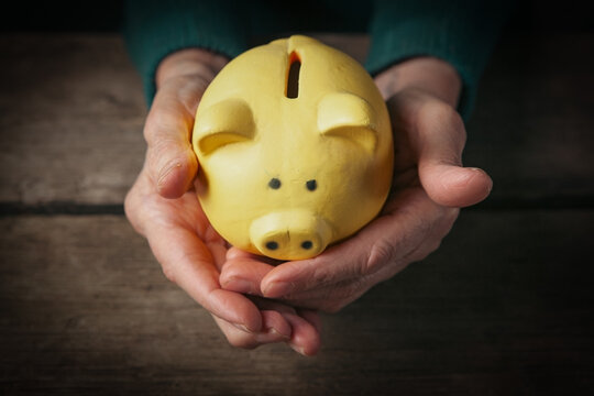 Piggy bank in hands on wooden background. Saving money concept