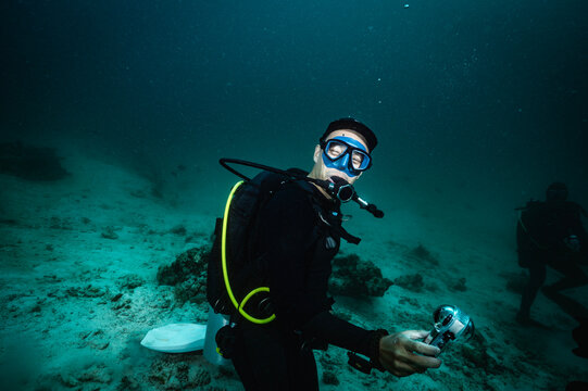 Happy man scuba diving underwater with a camera