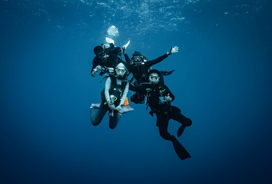 Four scuba divers posing for an underwater photo