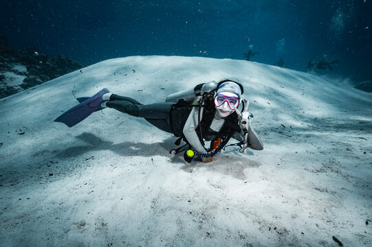 Happy female scuba diver gives peace sign underwater