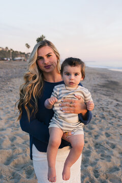 Young mother holds her baby on a sandy beach