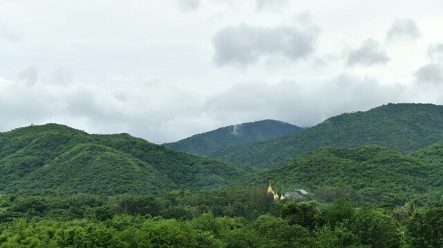 Dramatic cloud timelapse with dense white fog and mist rolling over a lush green mountain forest. Time-lapse footage.