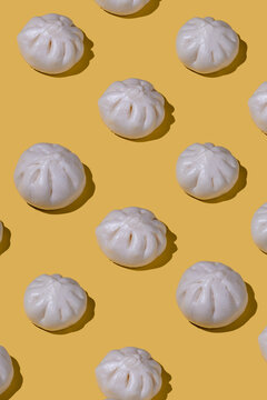 Steamed bao buns in a repeating pattern on yellow background