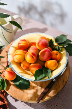 Fresh ripe apricots with leaves in a ceramic bowl