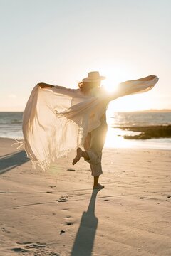 Playful woman with flowing scarf on a sunny beach