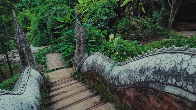 Temple staircase with stone naga sculptures in lush tropical forest, Ancient serpent railings at jungle Wat Phra Lat sanctuary with Buddhist architecture, Chiang Mai, Thailand 4k