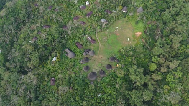 Wae Rebo traditional village on Flores island, an Unesco heritage site, down-looking aerial sunny view over the woody houses with villagers walking around, must-see destination in Indonesia and Asia