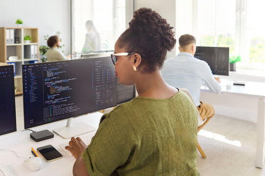 Programmers coding in office collaborate on software. Programmers work as a team with monitors and computers, building features for a startup. Teamwork powers modern software development.