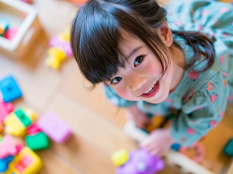 カラフルなブロック玩具で遊びながら上を見上げて笑う可愛い女の子