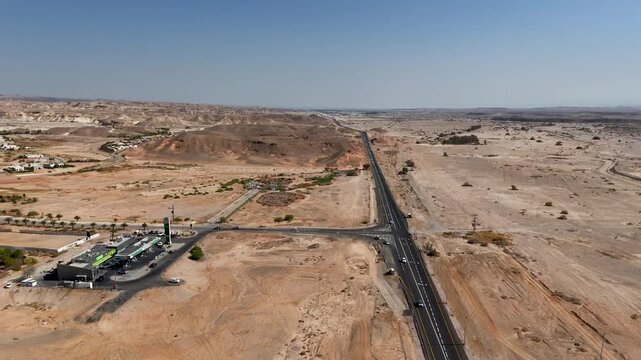 4K 60fps drone footage circling counterclockwise above the vast desert near Zukim, Israel, gradually revealing the Arava Road and surrounding rugged wilderness in a sweeping aerial panorama