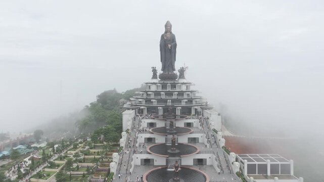 Aerial drone view of the giant Ba Den Mountain Buddha statue on Ba Den Mountain in Binh Minh, Tay Ninh, Vietnam, surrounded by scenic mountain landscapes.