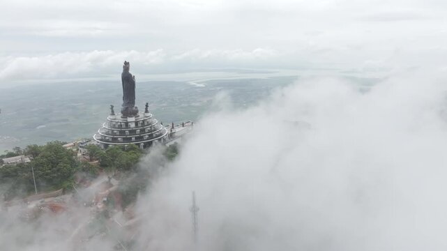 Aerial drone view of the giant Ba Den Mountain Buddha statue on Ba Den Mountain in Binh Minh, Tay Ninh, Vietnam, surrounded by scenic mountain landscapes.