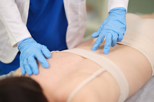 Doctor wearing gloves palpating processes vertebrae on patient back closeup. Treatment of spinal diseases concept