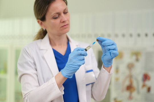 Nurse draws liquid medicine from ampoule into syringe for injection closeup. Intravenous administration of medicinal drug