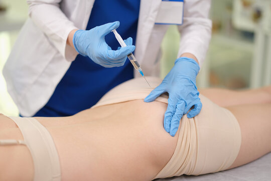 Doctor giving intramuscular injection into patient buttocks at clinic closeup. Antibacterial therapy cocnept