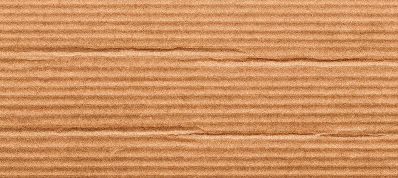 Close-up view of textured corrugated cardboard, highlighting the ribbed patterns and natural brown color, ideal for packaging or craft projects.