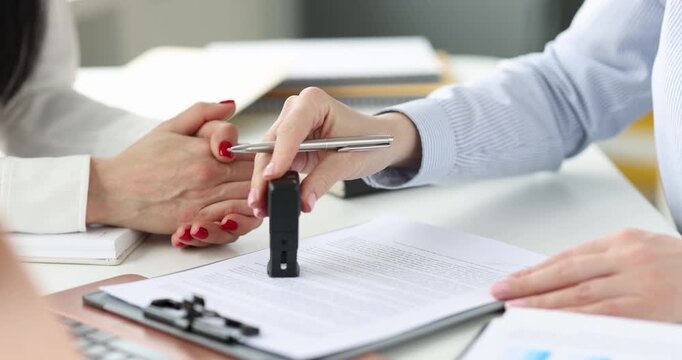 In a lively office setting, two people engage in a significant meeting. One person signs crucial papers while the other observes intently, creating a moment of focus and teamwork.