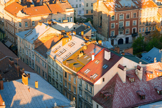 Golden hour sunlight illuminates aged rooftops of historic European city buildings