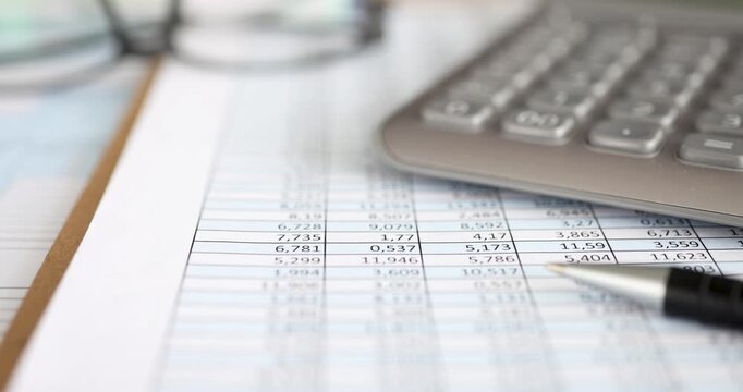 A hand engaging with a calculator while examining detailed financial spreadsheets outdoors during a bright afternoon. The gentle breeze adds to the focused atmosphere.