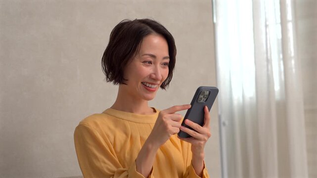 リビングでスマートフォンを使う女性