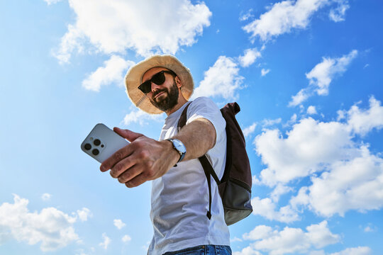 Bearded Man Taking Selfie with Smartphone Against Blue Sky